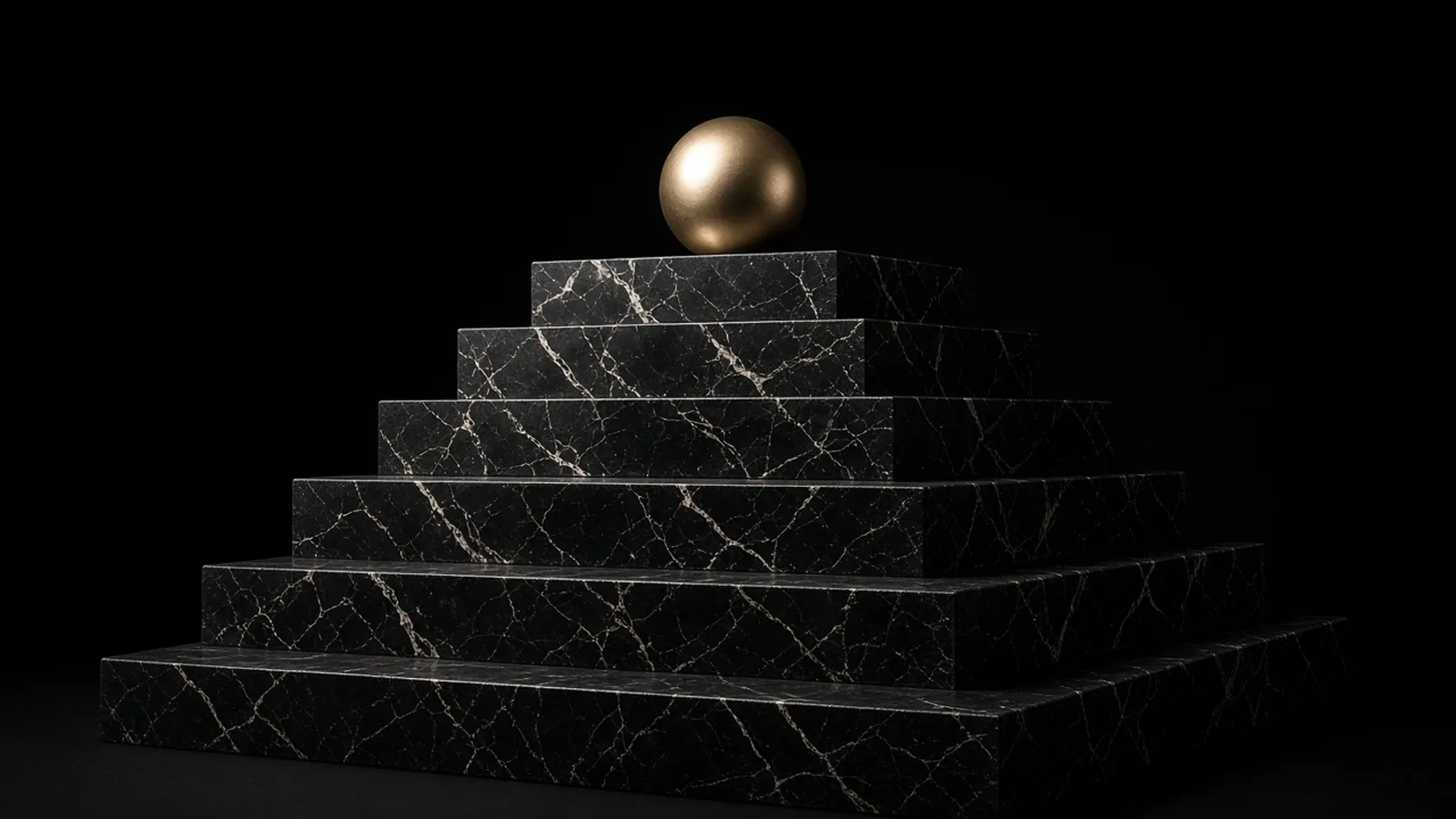 Stacked black marble steps with a gold sphere on top.